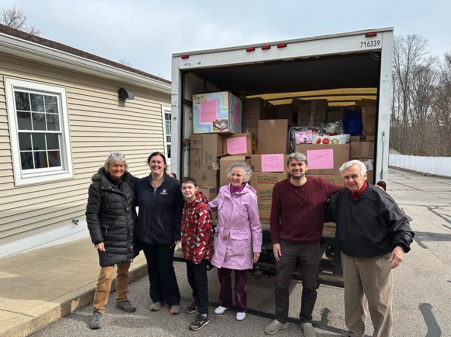 Volunteers standing in front of a moving truck packed with donation boxes
